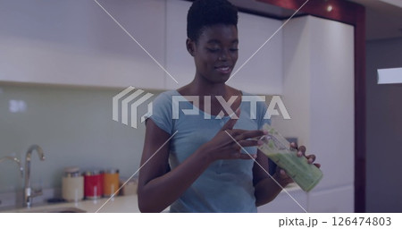 Holding green smoothie, woman in kitchen 126474803