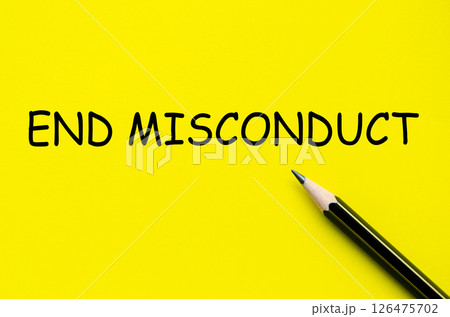 End misconduct text on yellow pad with pen representing the enforcement of integrity and accountability End misconduct text on yellow pad with pen representing the enforcement of integrity and accountability 126475702