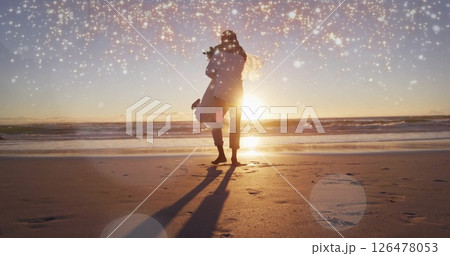 Image of light spots over biracial married couple embracing at seaside 126478053