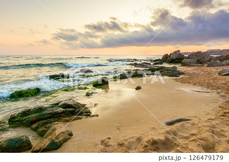 summer vacation landscape at the beach. dramatic seascape at sunrise. calm wave washing the coast with sand and rocks. beautiful view of sky with sun and cloud above horizon summer vacation landscape at the beach. dramatic seascape at sunrise. calm wave washing the coast with sand and rocks. beautiful view of sky with sun and cloud above horizon 126479179
