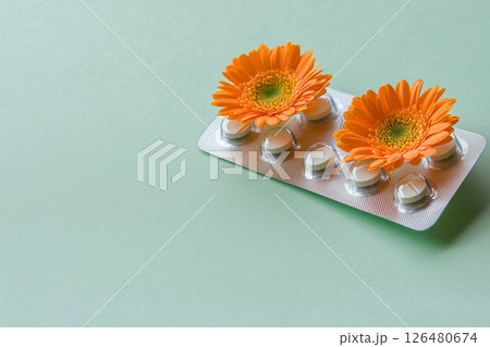 pills in a blister pack with orange flowers on green background, allergy to flowers 126480674