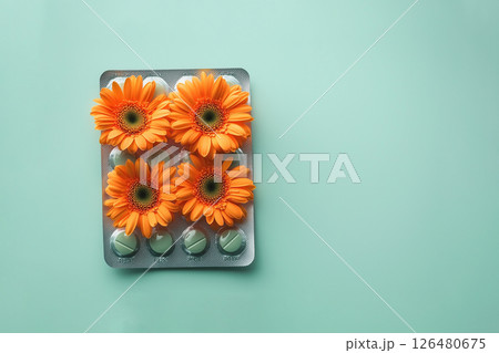 pills in a blister pack with orange flowers on green background, allergy to flowers 126480675
