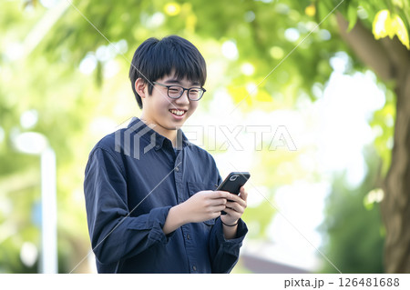 明るい表情でスマホを持つ黒いシャツを着た男子生徒 126481688