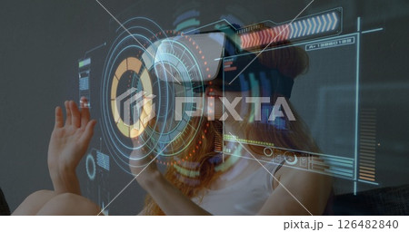 Woman using VR headset interacting with digital interface, exploring virtual reality 126482840