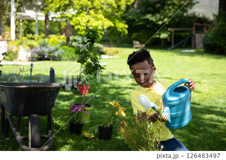 Young boy watering plants in garden, enjoying outdoor gardening activity, copy space Young boy watering plants in garden, enjoying outdoor gardening activity, copy space 126483497