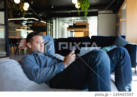 Relaxing in modern office, man using smartphone and listening to music Relaxing in modern office, man using smartphone and listening to music 126483507