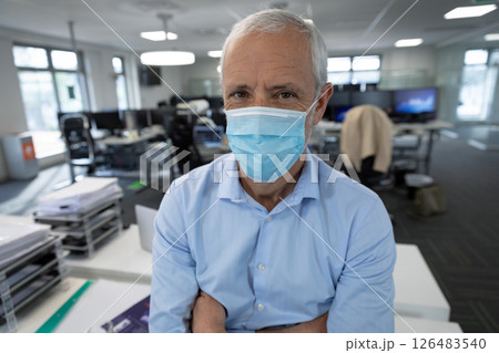Senior man wearing mask standing confidently in modern office environment Senior man wearing mask standing confidently in modern office environment 126483540