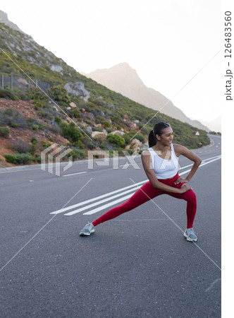 Woman stretching on mountain road, enjoying outdoor fitness in nature, copy space 126483560
