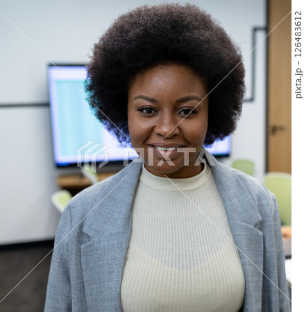 African American woman smiling confidently in office, wearing professional attire 126483612