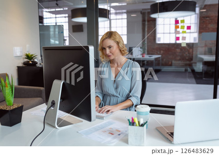 Professional woman typing on computer at office desk, focused and productive 126483629