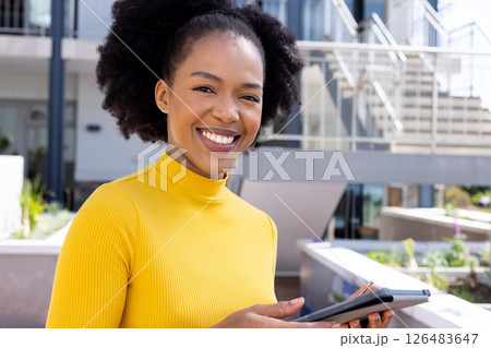 Smiling woman holding tablet outdoors, enjoying sunny day at modern office Smiling woman holding tablet outdoors, enjoying sunny day at modern office 126483647