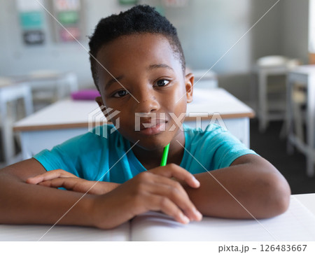In school, African American boy holding pencil, looking thoughtful in classroom 126483667