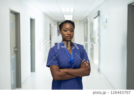Confident nurse in scrubs standing in hospital corridor, arms crossed 126483707