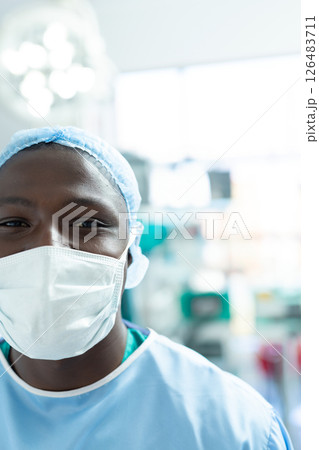 Smiling healthcare professional wearing mask and scrubs in hospital operating room 126483711