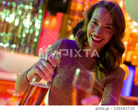 Smiling woman pouring champagne in nightclub, enjoying vibrant party atmosphere Smiling woman pouring champagne in nightclub, enjoying vibrant party atmosphere 126483719