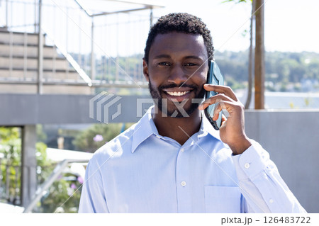 Talking on smartphone, businessman outdoors on sunny day, smiling brightly Talking on smartphone, businessman outdoors on sunny day, smiling brightly 126483722