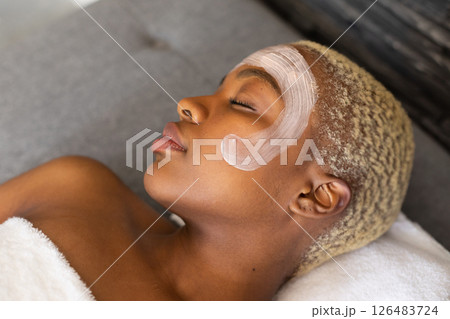 Relaxing at home, woman enjoying facial treatment with soothing cream on face 126483724