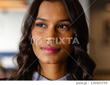 Confident woman with wavy hair looking away, thinking in modern office 126483739