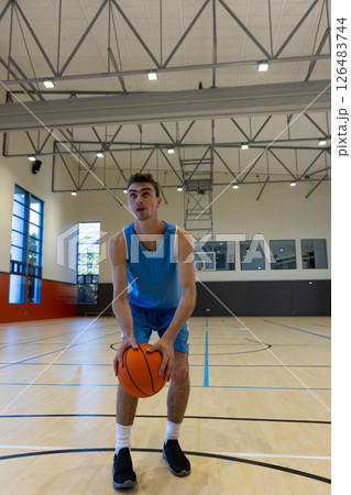Young man in gym holding basketball, preparing to make shot 126483744