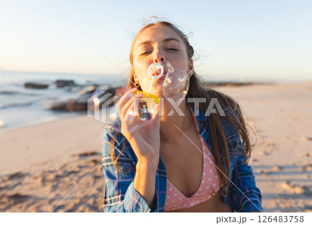 Young woman blowing bubbles on beach, enjoying sunset and ocean breeze 126483758