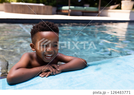 Smiling African American boy enjoying swimming in pool on sunny day 126483771