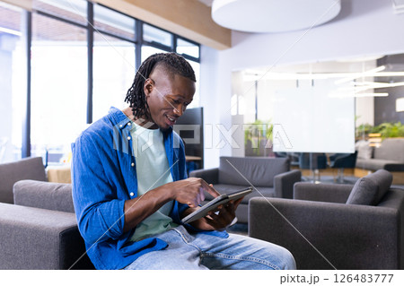 Man using tablet in modern office lounge, focusing on digital tasks, copy space 126483777