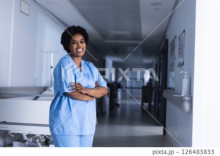 African American nurse in scrubs smiling confidently in hospital corridor, copy space 126483833