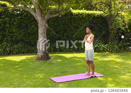 Woman practicing yoga on mat in garden, embracing tranquility and nature, copy space Woman practicing yoga on mat in garden, embracing tranquility and nature, copy space 126483848