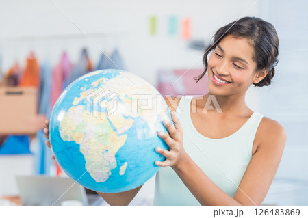 Smiling woman holding globe in office, exploring global business opportunities Smiling woman holding globe in office, exploring global business opportunities 126483869