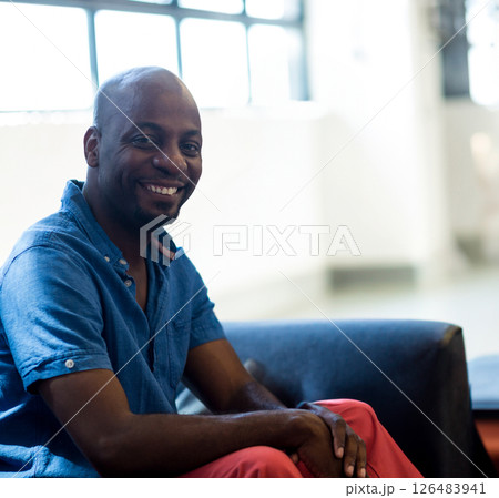 Smiling man in casual attire sitting on sofa in modern office lounge, copy space 126483941