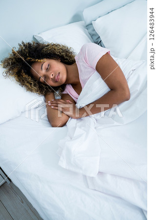 Peacefully sleeping woman resting comfortably in cozy bed at home 126483944