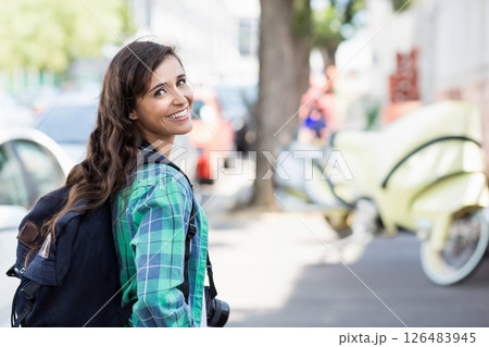 Exploring city street, woman with backpack holding camera, feeling adventurous, copy space 126483945