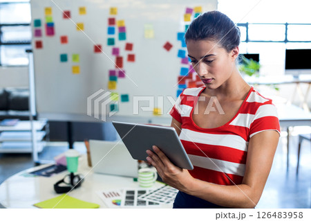 Focused woman using tablet in modern office with colorful sticky notes, copy space 126483958