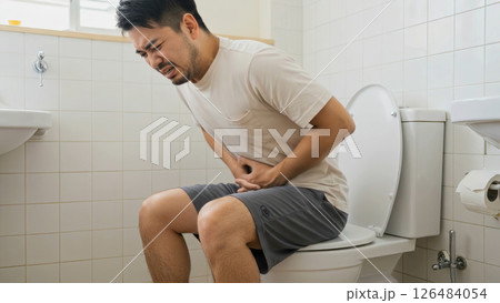 トイレで腹痛の痛みを堪える、ヒゲの生えた白いTシャツの男性 トイレで腹痛の痛みを堪える、ヒゲの生えた白いTシャツの男性 126484054