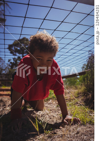 Child crawling under net outdoors, smiling and enjoying boot camp activity Child crawling under net outdoors, smiling and enjoying boot camp activity 126484281