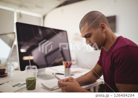 Young man using smartphone at desk in modern office, focusing on work, copy space 126484284