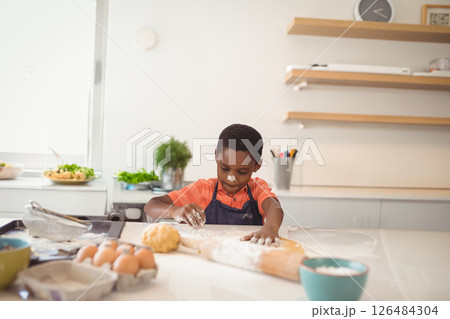 Young boy baking at home, concentrating while kneading dough on kitchen counter, copy space Young boy baking at home, concentrating while kneading dough on kitchen counter, copy space 126484304