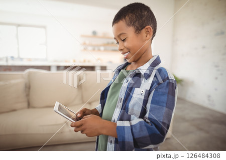 Smiling boy using smartphone at home, enjoying technology in living room, copy space 126484308