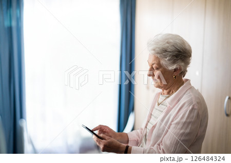 Elderly woman using smartphone at home, staying connected with family, copy space 126484324