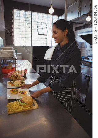 Chef preparing delicious gourmet burgers and fries in modern cafe kitchen, copy space Chef preparing delicious gourmet burgers and fries in modern cafe kitchen, copy space 126484356