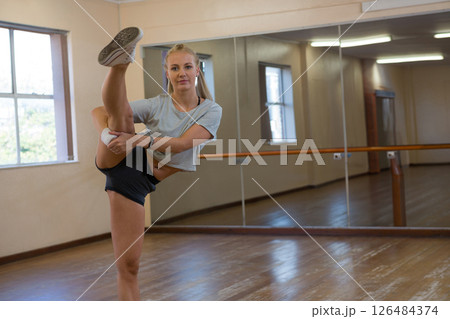 Young woman practicing dance moves in studio, showing flexibility and focus, copy space Young woman practicing dance moves in studio, showing flexibility and focus, copy space 126484374