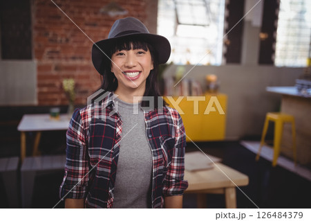 Smiling woman in hat enjoying casual day at trendy urban cafe 126484379