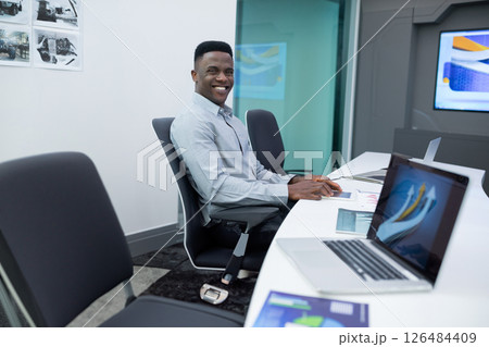Smiling businessman using laptop and tablet in modern office meeting room, copy space Smiling businessman using laptop and tablet in modern office meeting room, copy space 126484409