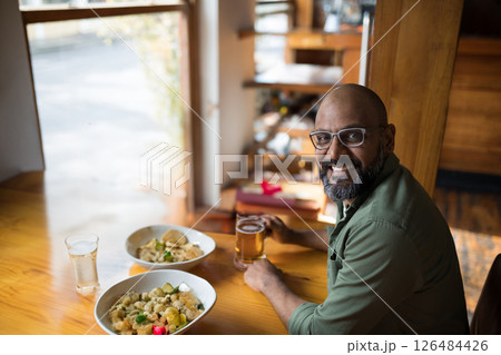 Smiling man enjoying Mexican food and beer at cozy restaurant table, copy space 126484426