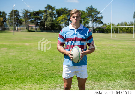 Holding rugby ball, athlete wearing striped jersey on field, looking determined, copy space Holding rugby ball, athlete wearing striped jersey on field, looking determined, copy space 126484519