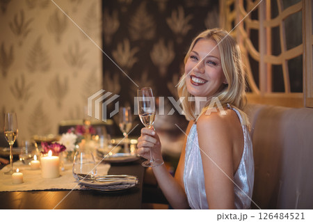 Woman enjoying dinner with friends, holding champagne glass, smiling warmly, copy space Woman enjoying dinner with friends, holding champagne glass, smiling warmly, copy space 126484521