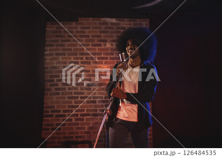 Musician performing passionately on stage with vintage microphone, enjoying moment, copy space 126484535