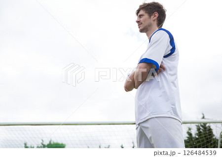 Soccer player standing confidently on field, wearing white and blue uniform, copy space 126484539