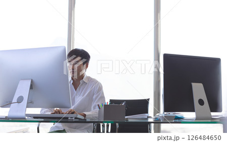 Asian man working on desktop computer in modern office, focusing on task, copy space Asian man working on desktop computer in modern office, focusing on task, copy space 126484650