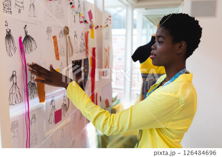 Fashion designer reviewing sketches on inspiration board in modern studio, copy space Fashion designer reviewing sketches on inspiration board in modern studio, copy space 126484696